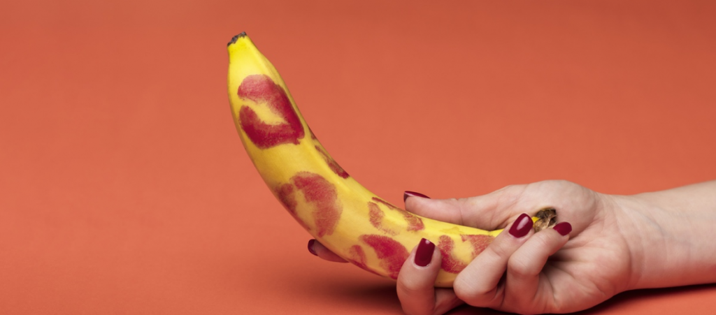 une main tient une banane avec des traces de rouge à lèvres