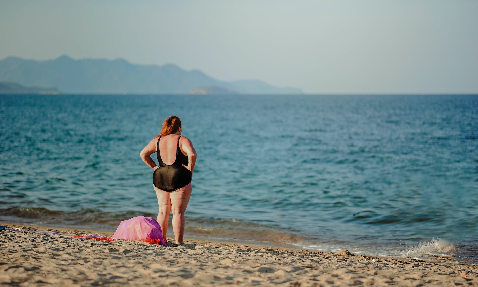 femme en maillot de bain qui regarde la mer 