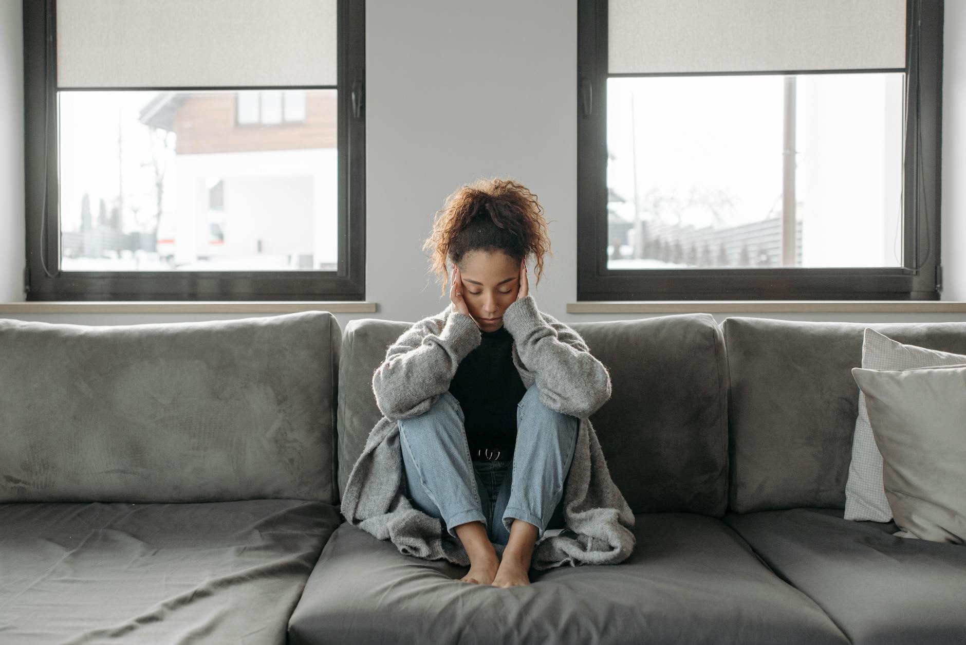 femme assise sur un canapé qui se tient la tête 