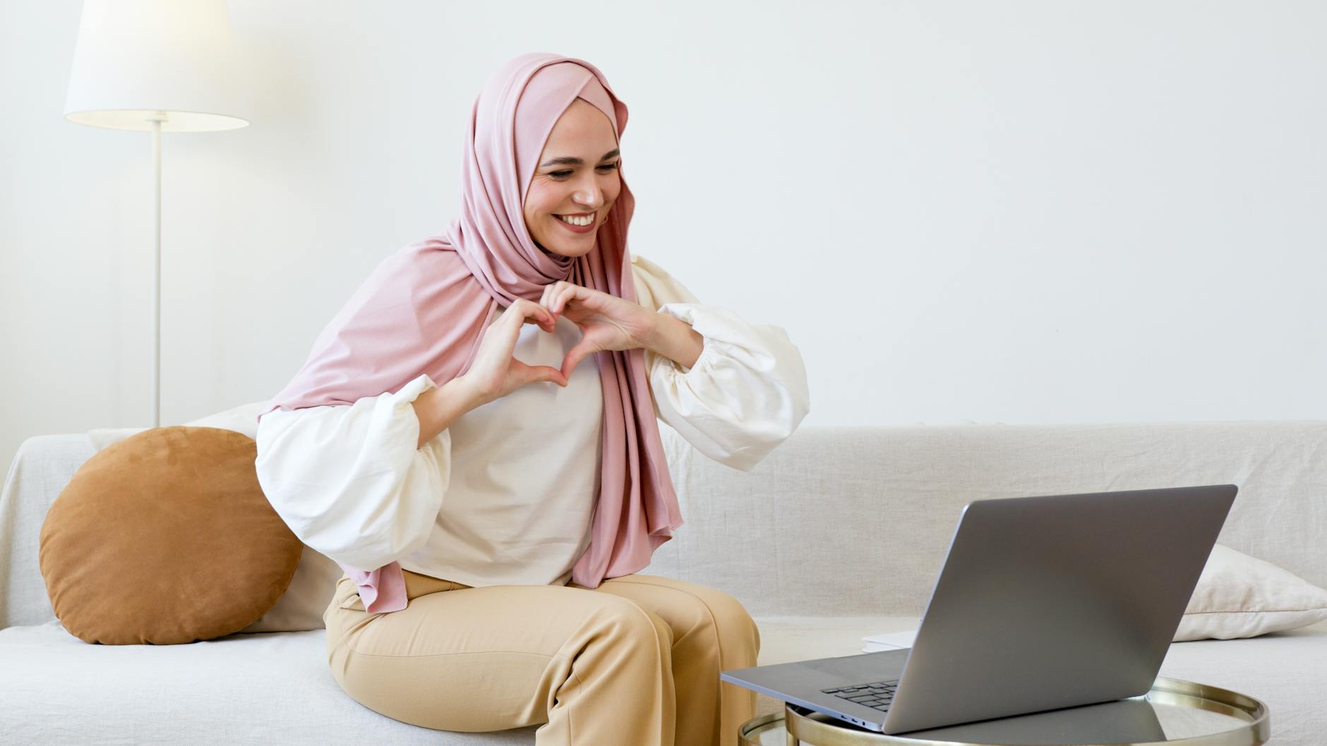 woman in pink hijab and white long sleeve shirt sitting on white couch